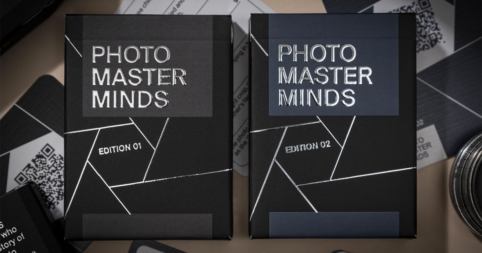 Two boxes labeled Photo Master Minds Edition 01 and Edition 02 with geometric designs, lying among various photographic equipment.