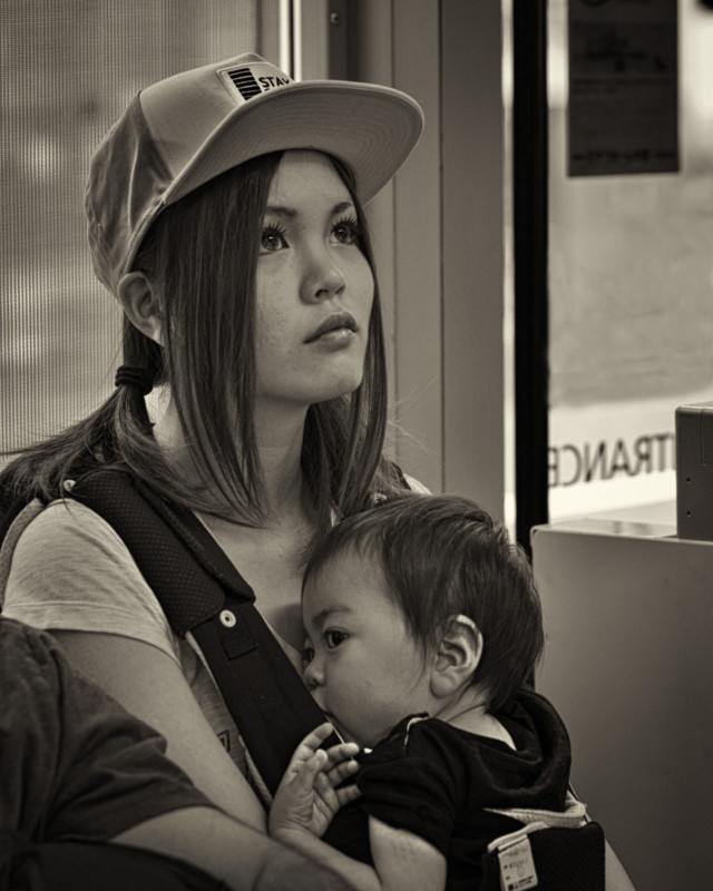 A woman holding a child in a carrier on her chest